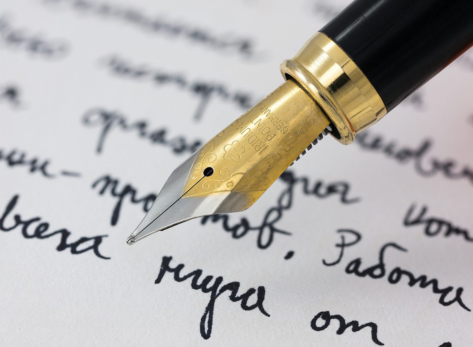 A close-up of a fountain pen writing in ink on paper