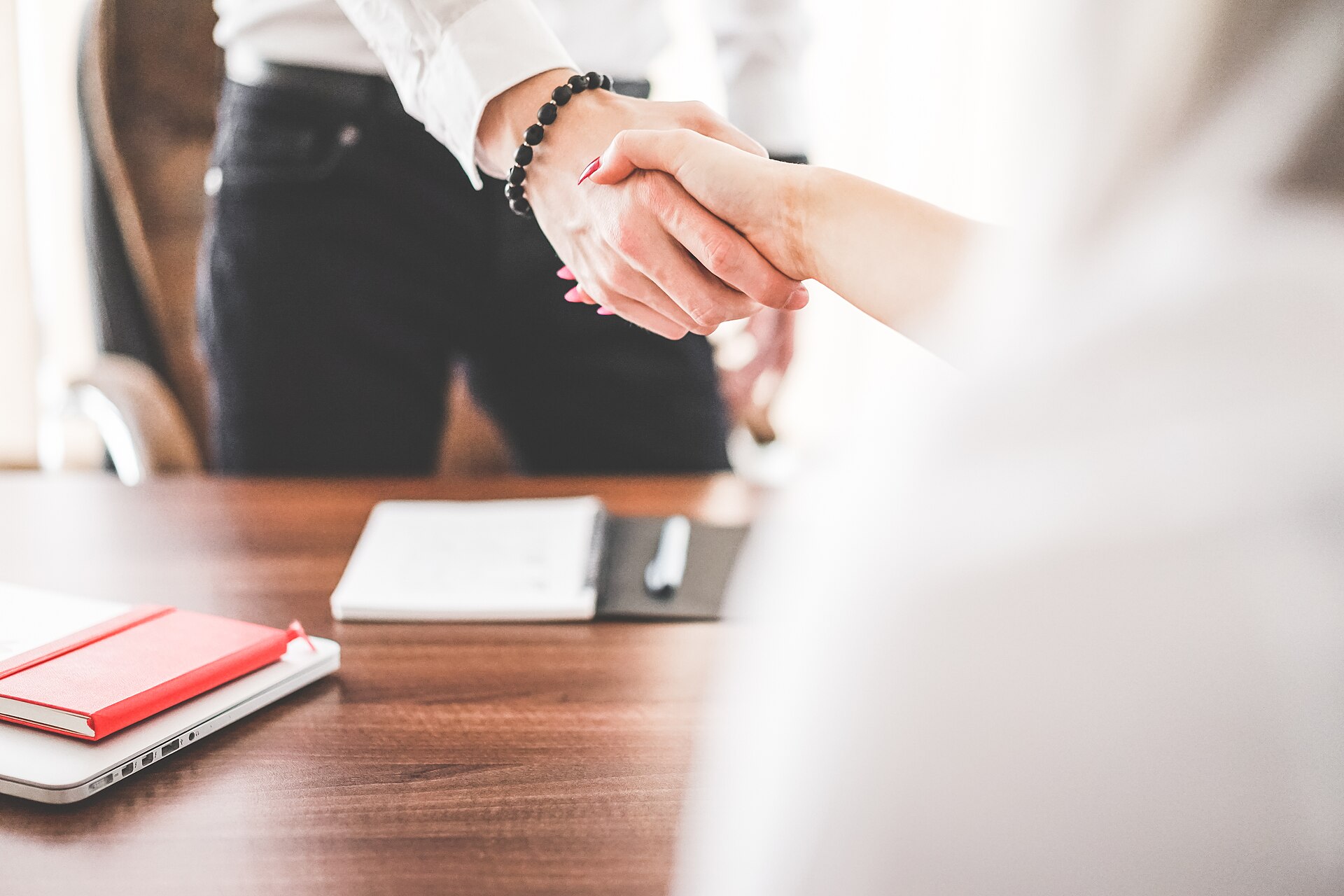 A business handshake across a desk — the moment a renegotiated agreement is settled.