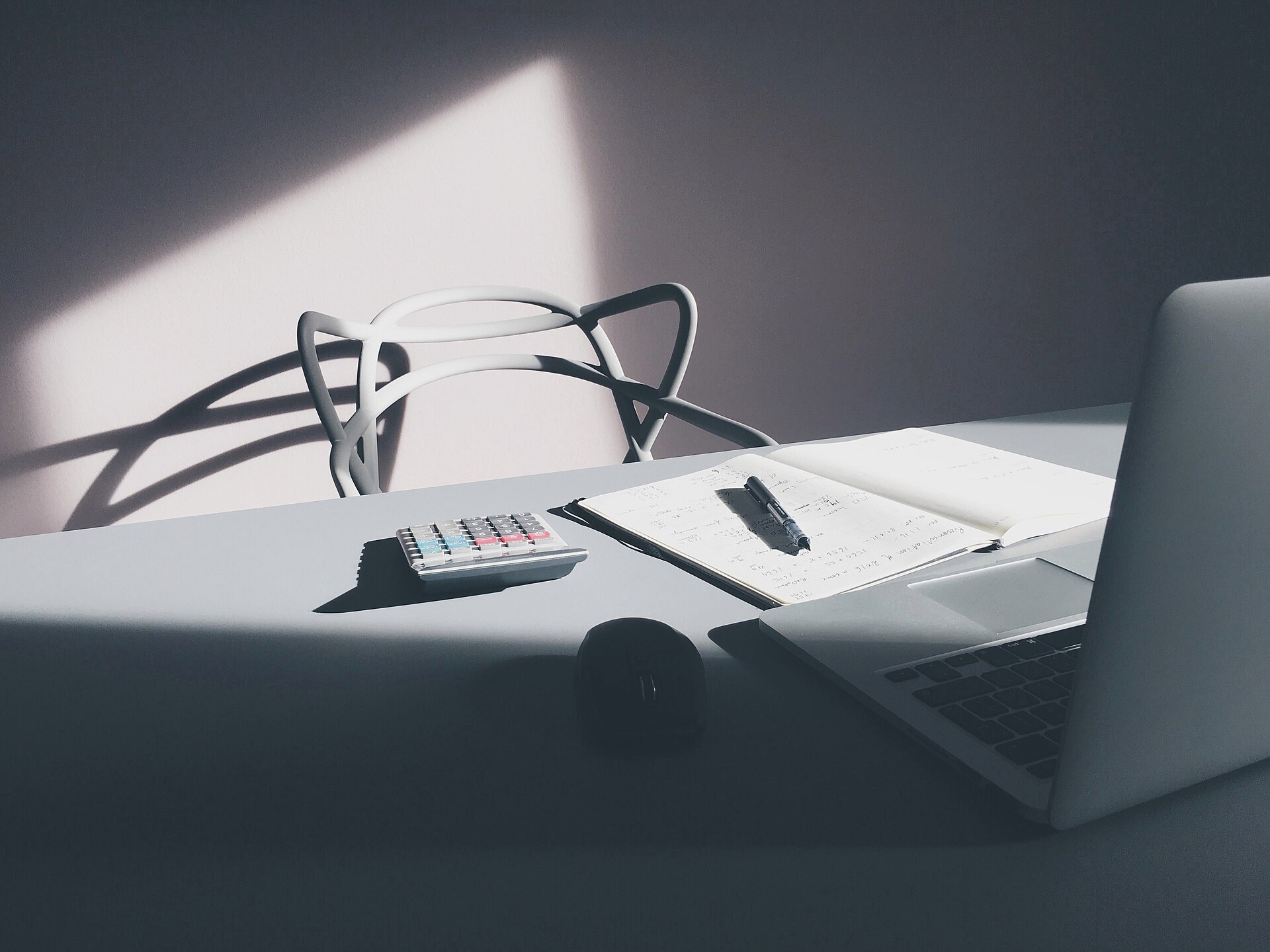 A laptop and a calculator on a clean desk — the actual tools of cost-reduction work.