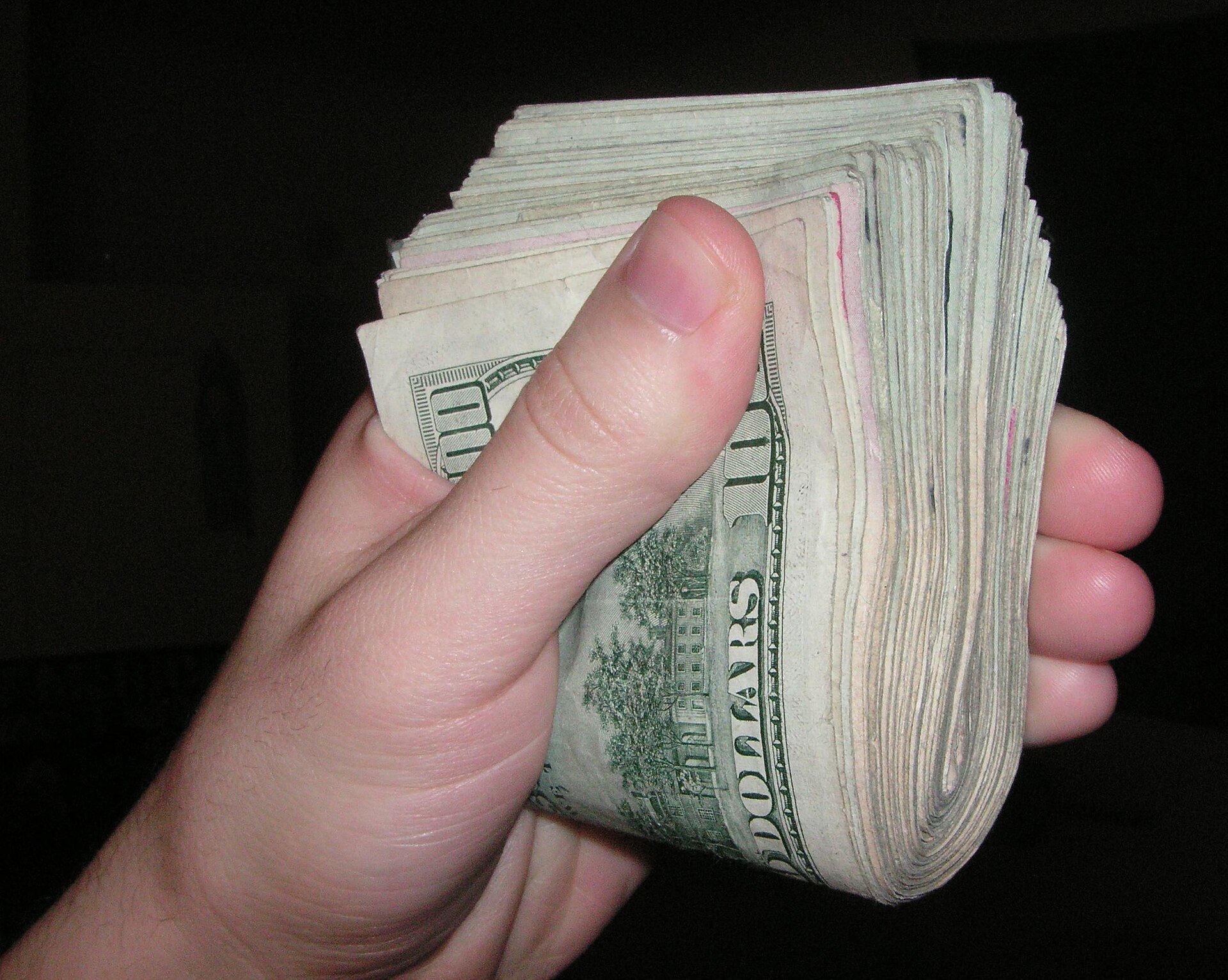A close-up of fanned American currency — the actual cash a settlement releases back to the operating account.
